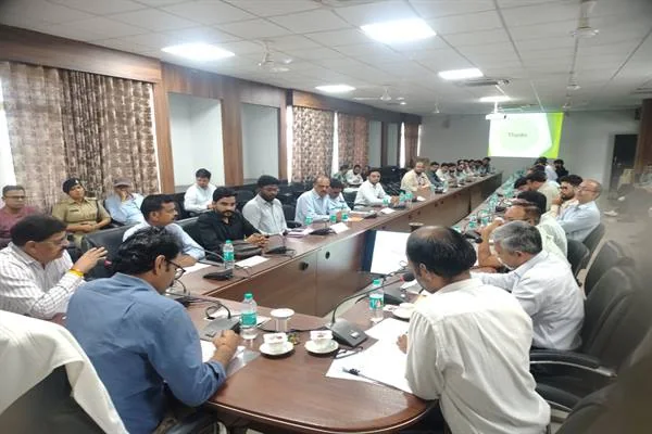 सम्मेलन कक्ष में लंबी मेज के दोनों ओर बैठे बैंक अधिकारी और जिला अधिकारी बैठक करते हुए