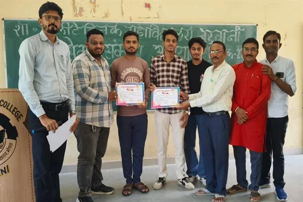 महाविद्यालय के कक्ष में दो प्रमाणपत्र लिए विद्यार्थियों के साथ खड़े शिक्षक और अन्य विद्यार्थी